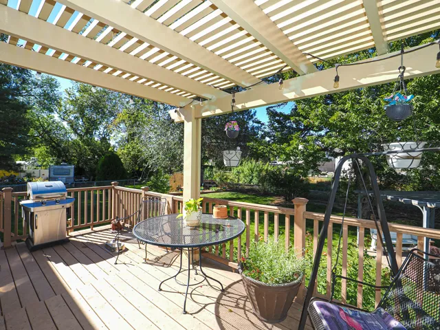 Deck with a slatted pergola, wood-finish railing, and string lighting