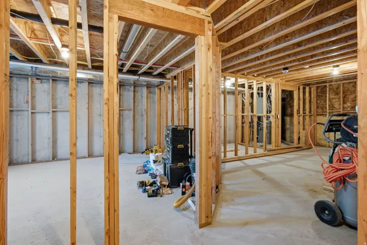 Unfinished lower level featuring concrete flooring and exposed wooden framing