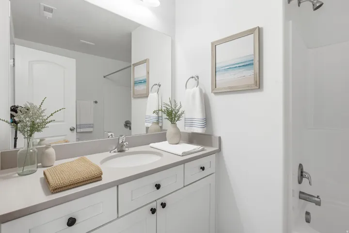 White vanity with black cabinet hardware, integrated sink, and light-toned countertop