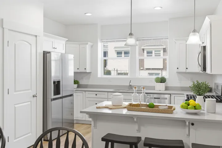White shaker cabinetry, stainless steel appliances, recessed lighting, pendant lighting, and light-toned countertops