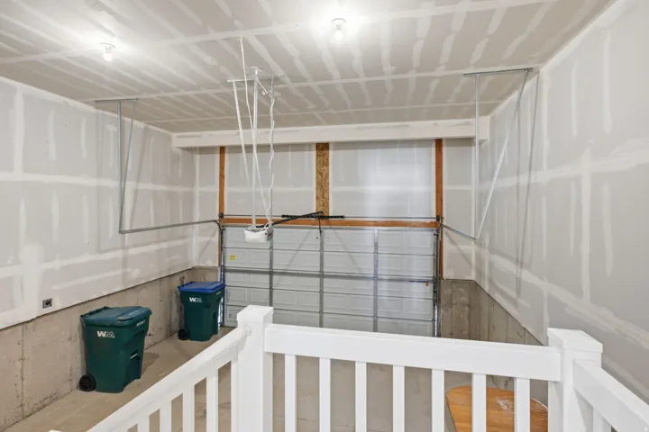 Garage featuring a metal overhead door, concrete foundation, and unfinished drywall walls and ceiling