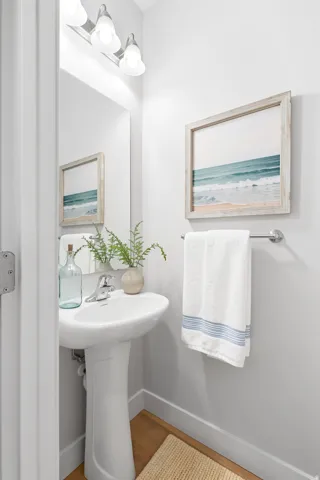 Pedestal sink with chrome faucet, large wall mirror, and overhead vanity lighting