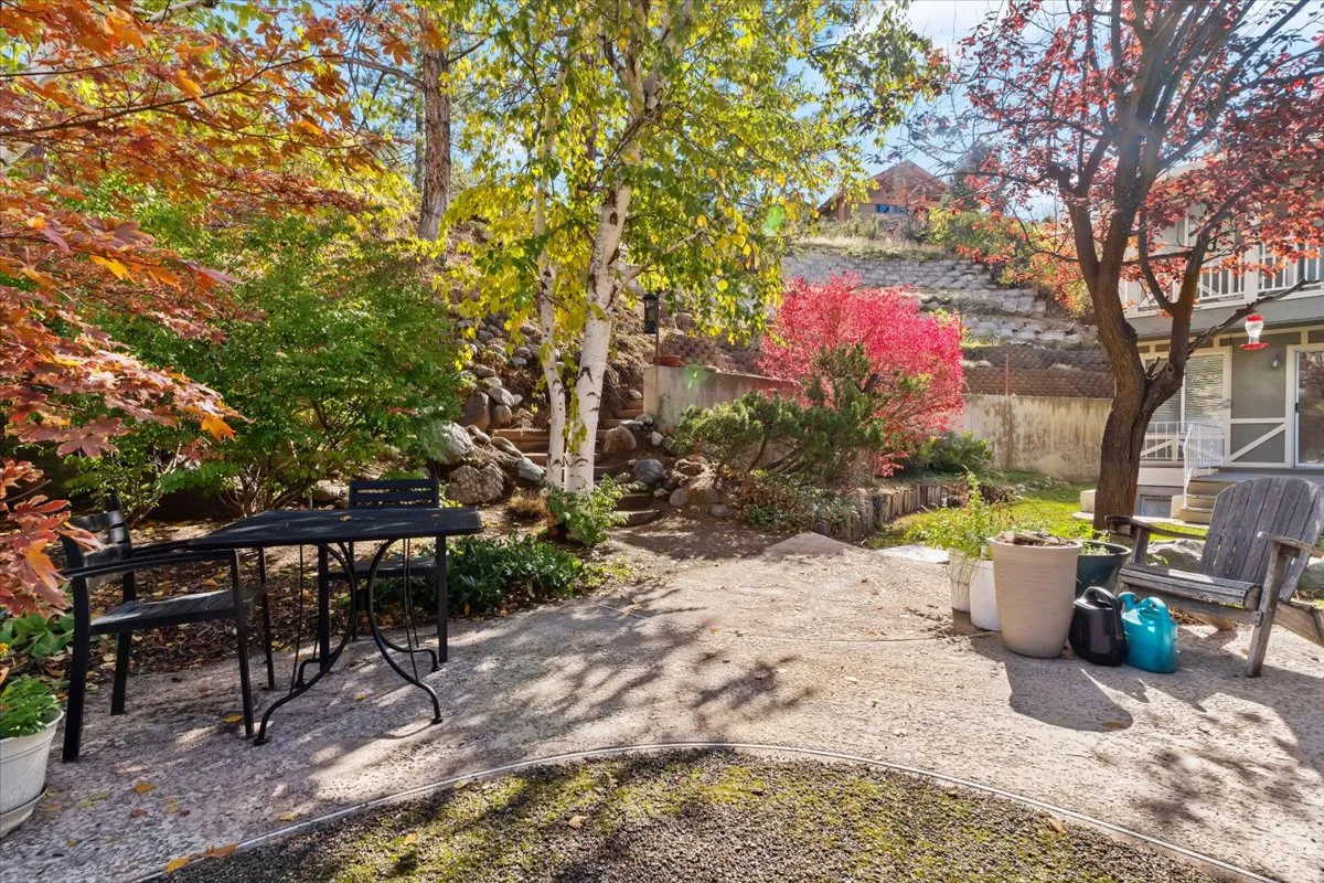 Tiered landscaping with mature trees, established plantings, and a stone pathway
