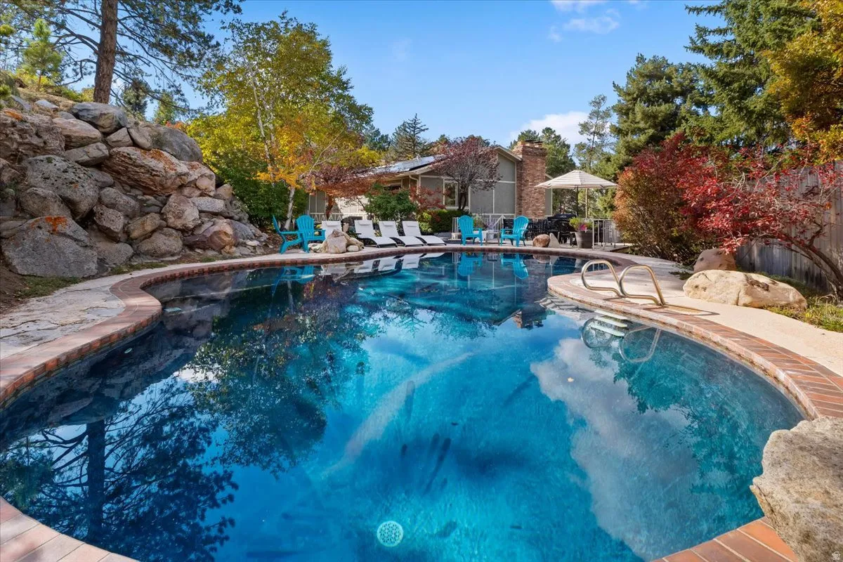 Curved swimming pool with brick coping, flagstone decking, and built-in entry steps