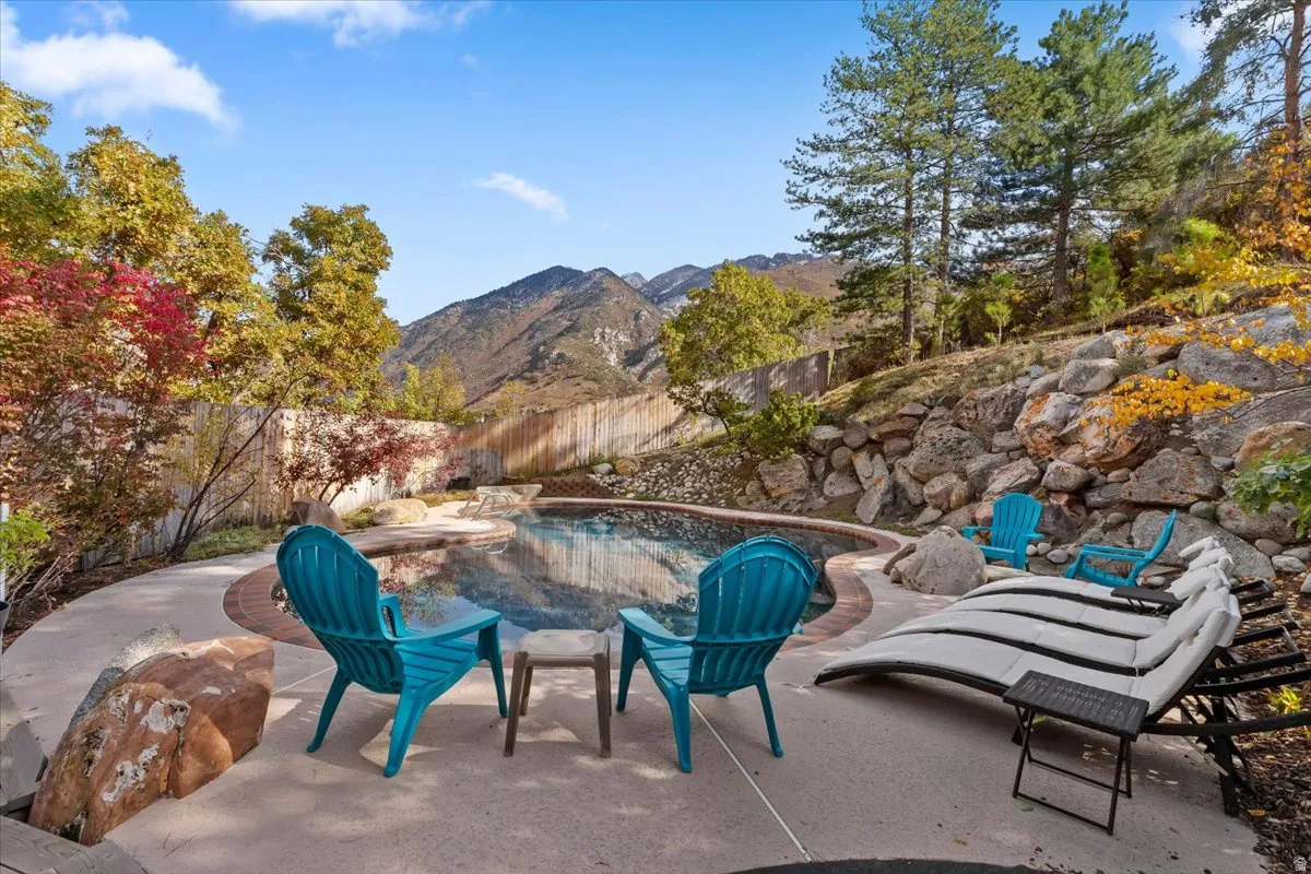 Private outdoor pool area featuring a natural rock retaining wall and mature trees