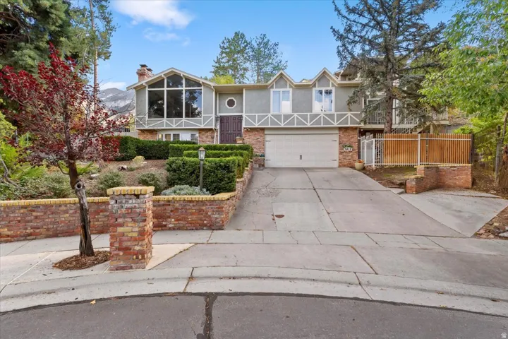 Stucco exterior with a prominent window wall, brick accents, attached garage, and established landscaping