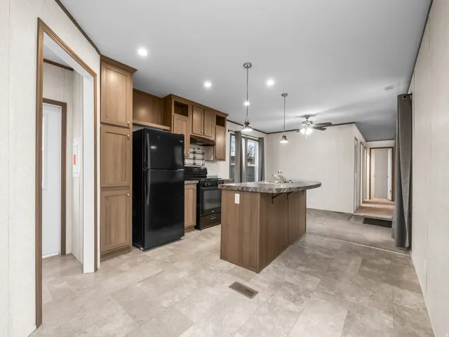 Kitchen featuring wood-finish cabinetry, black appliances, a central island with sink, pendant lighting, and recessed ceiling lights