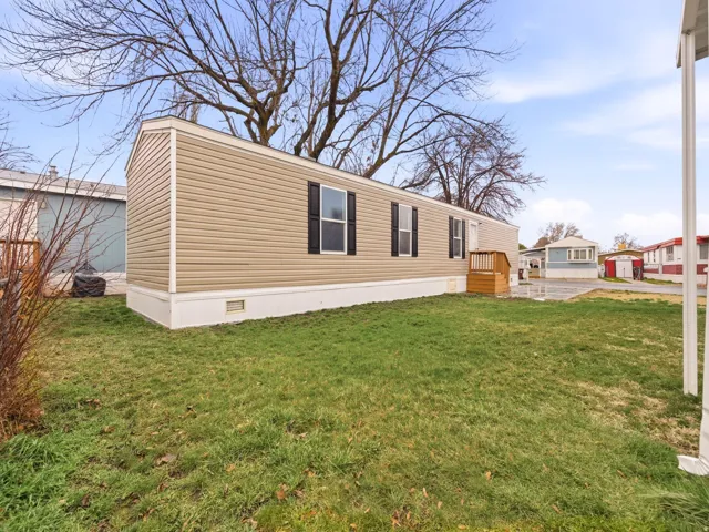 Tan vinyl siding exterior with black window shutters and white trim details