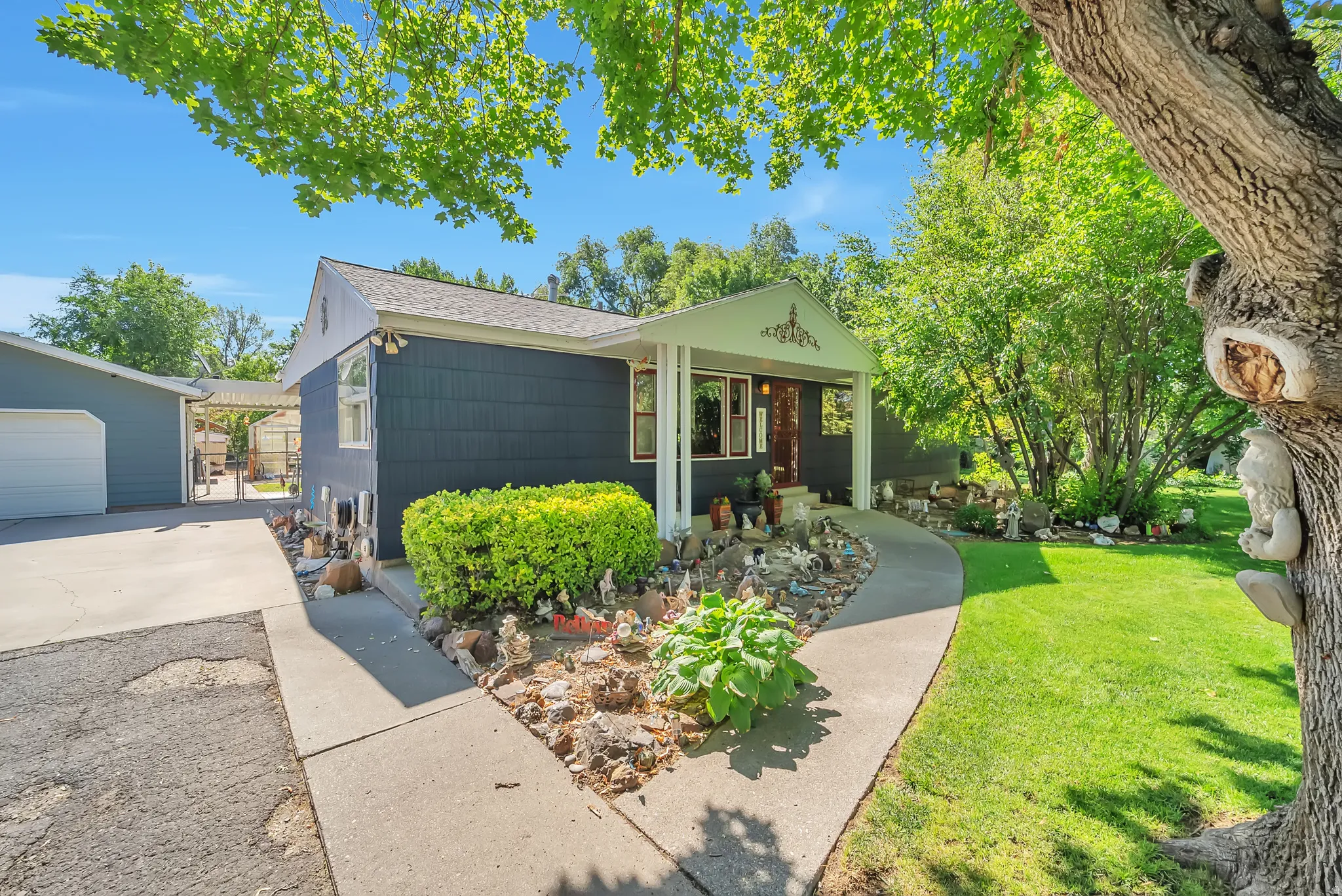 Paved driveway, covered front porch, established landscaping, and detached garage structure