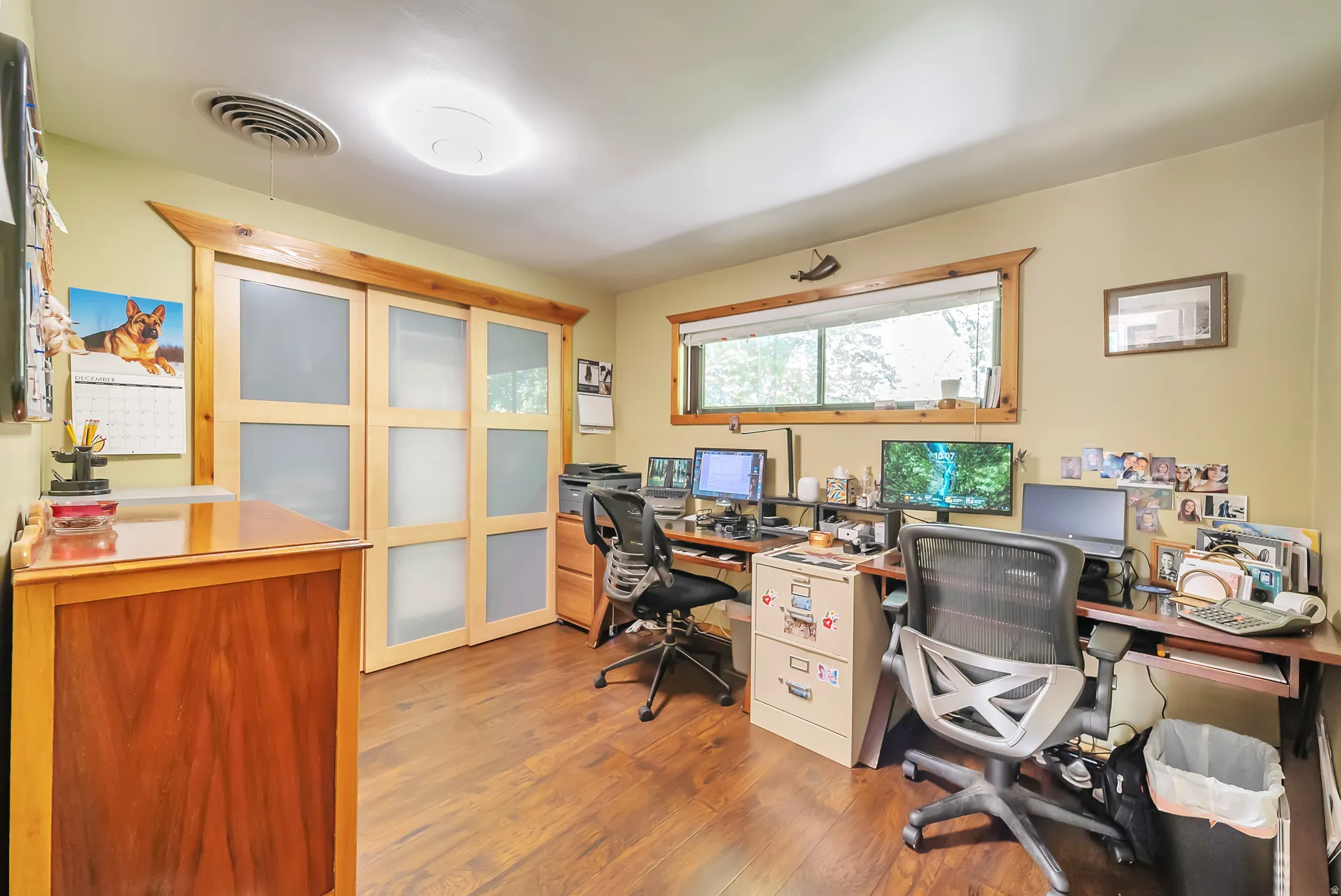 Wood-finish flooring, sliding closet doors with frosted panels, and a large window with wood trim