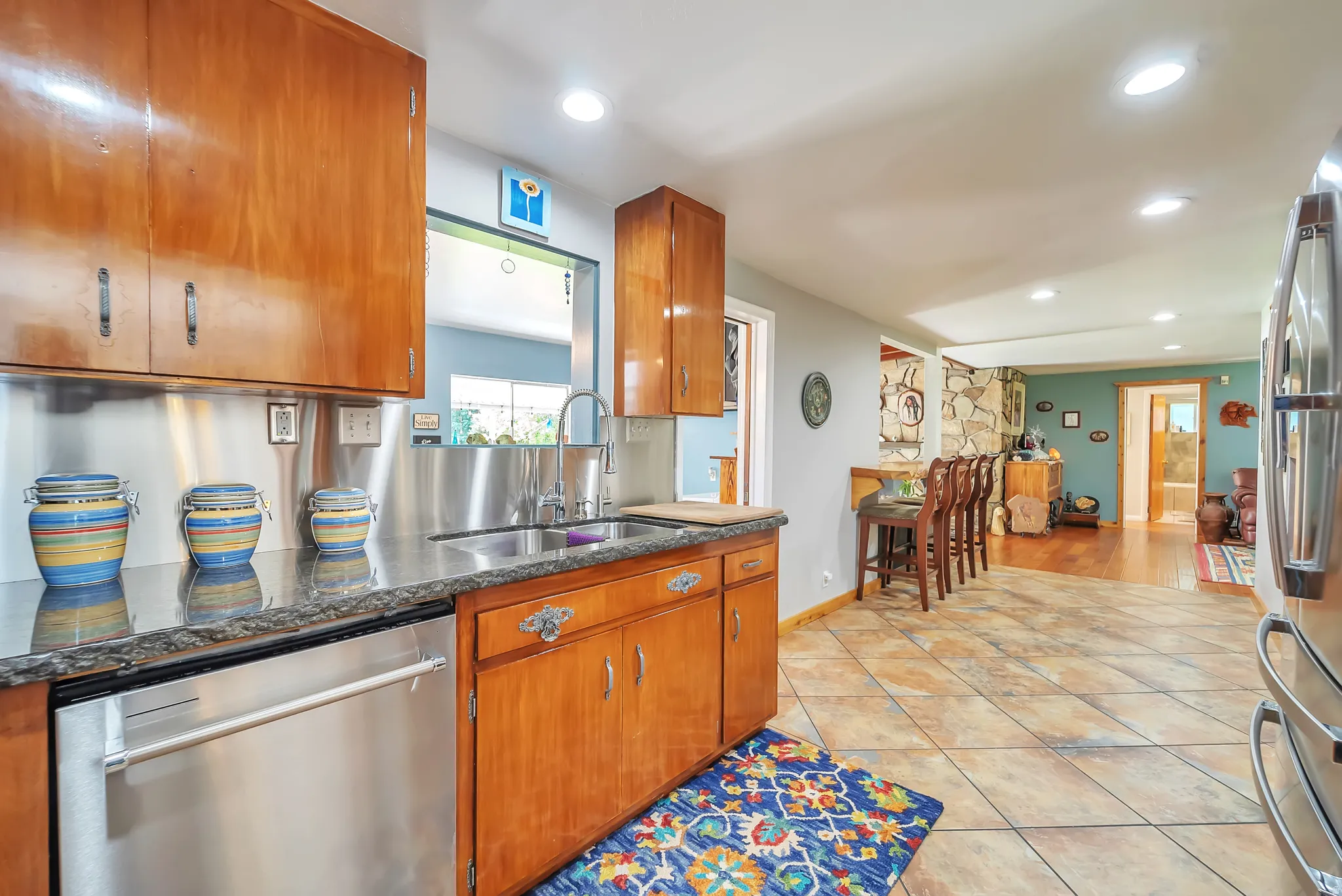 Kitchen featuring wood cabinetry, stainless steel appliances, dark stone countertops, and a stainless steel backsplash