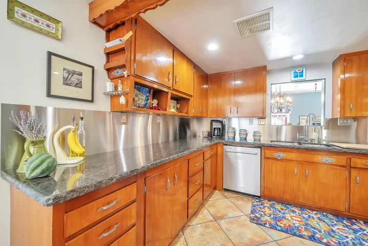 Wood-finish cabinetry paired with dark countertops and a stainless steel backsplash