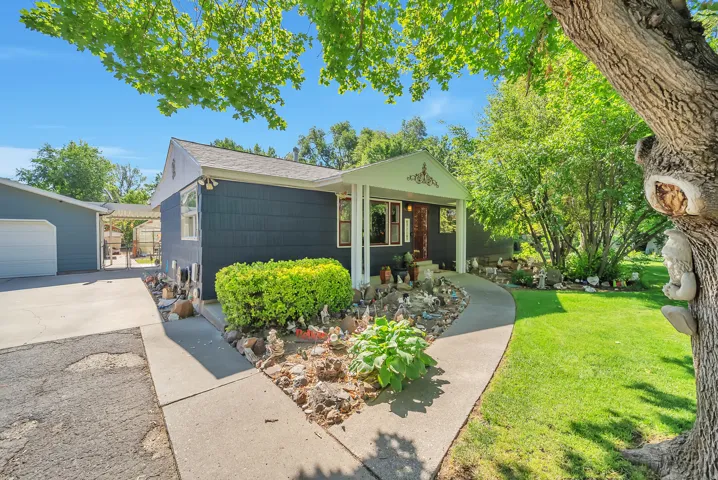 Paved driveway, covered front porch, established landscaping, and detached garage structure