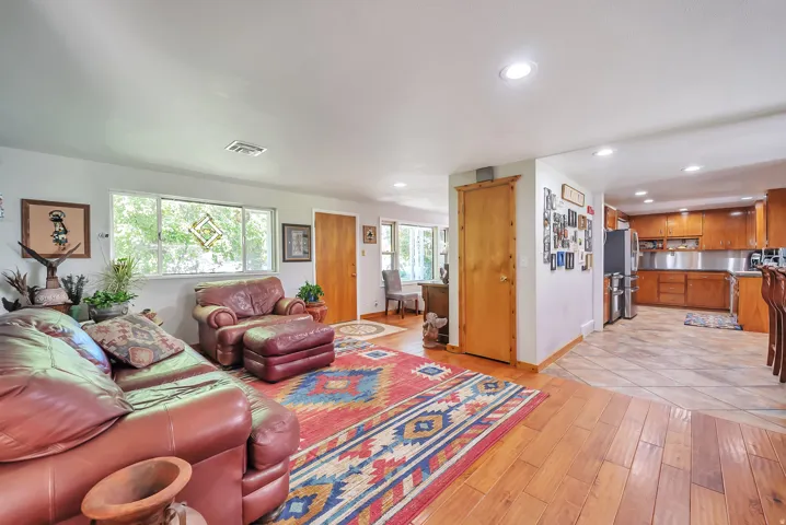 Spacious open-concept living area featuring hardwood flooring, recessed ceiling lighting, and large windows with natural light