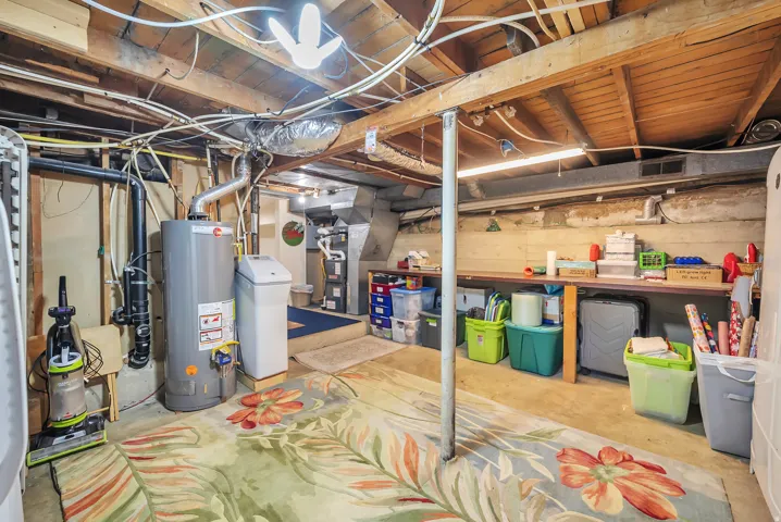 Basement utility area featuring a water heater, water softener, and accessible exposed joists
