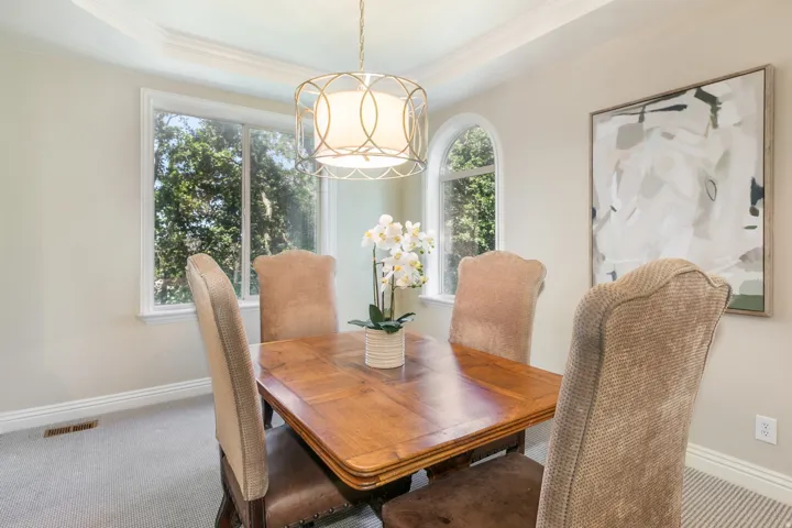 Tray ceiling with crown molding, chandelier lighting, arched window, and picture window