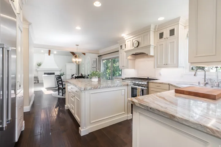Gourmet kitchen featuring a substantial island with stone countertops, stainless steel appliances, extensive cabinetry, and wood-finish flooring