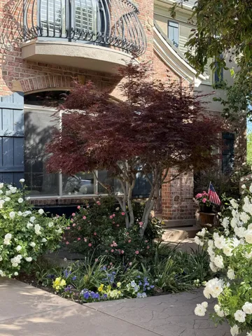 Brick exterior with decorative wrought iron balcony and intricate landscaping