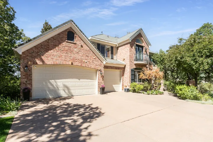 Brick exterior with a tiled roof, arched garage door openings, and a second-story balcony with wrought iron railing