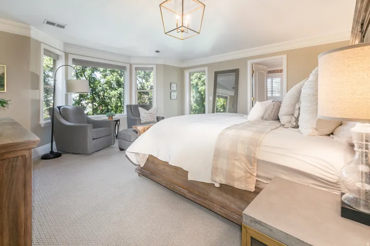 Bay window with multiple panels, crown molding, a decorative ceiling light fixture, and light-colored carpeting