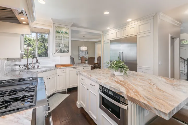 Gourmet kitchen featuring white cabinetry, stainless steel appliances, a large center island with a built-in microwave, and wood-finish flooring