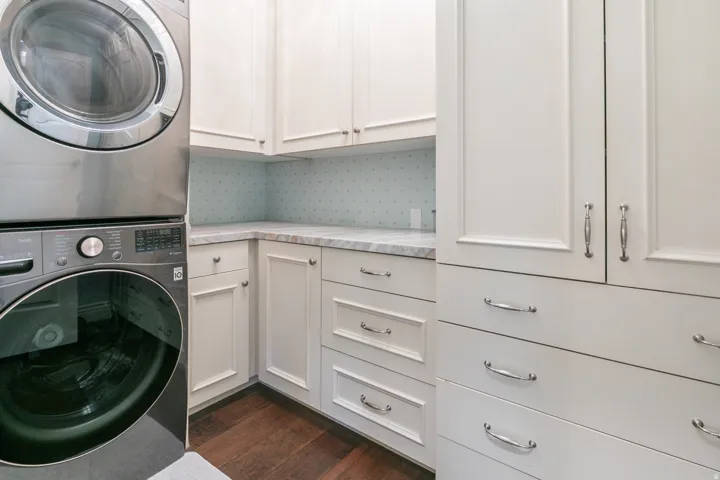 White shaker cabinetry, light-toned countertop, wood-finish flooring, and chrome hardware