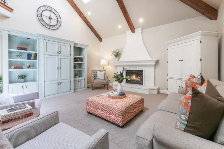 Vaulted ceiling with exposed wood beams, built-in cabinetry, brick fireplace, and skylight