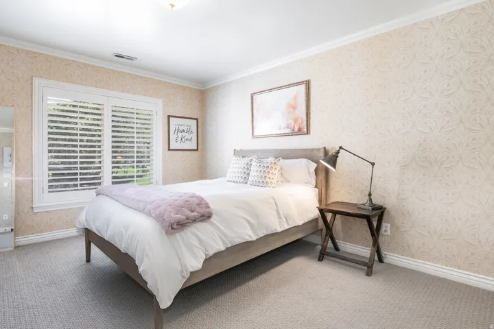 Textured wallpaper, crown molding, white window shutters, wall-to-wall carpeting, and a flush mount ceiling light