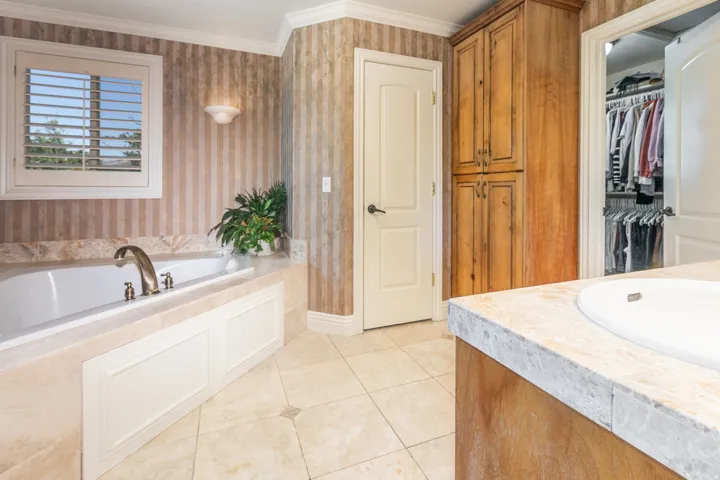 Built-in soaking tub with decorative paneling and brass-finish fixtures