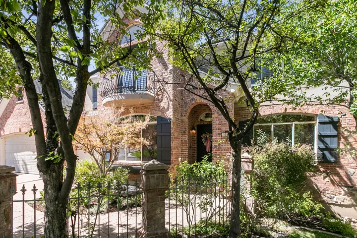 Brick exterior with arched entryways, a Juliet balcony with wrought iron railing, and dark louvered shutters