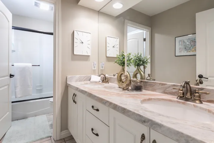Dual vanity with stone countertop, undermount sinks, and antique brass finish faucets