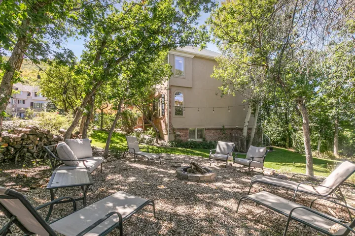 Private outdoor gathering space featuring a built-in fire pit, string lighting, and extensive gravel hardscaping