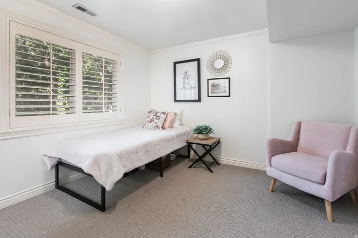 Window with plantation shutters, crown molding, and neutral carpeting