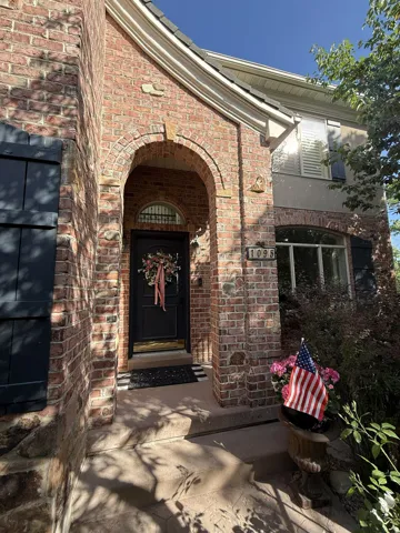 Brick exterior featuring an arched entry, dark front door with gold hardware, and decorative shutters