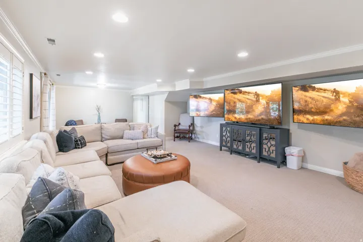 Recessed ceiling lighting, crown molding, plantation shutters, and light-toned carpeting throughout