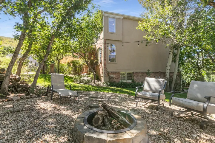 Backyard featuring a stone fire pit, gravel ground cover, and mature trees providing natural shade