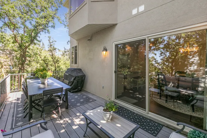 Expansive exterior deck featuring composite decking, a metal railing, and a wall-mounted light fixture
