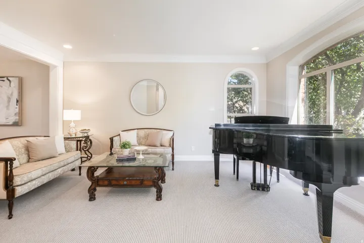 Spacious living area featuring neutral wall tones, crown molding, arched windows, recessed lighting, and light-toned carpeting