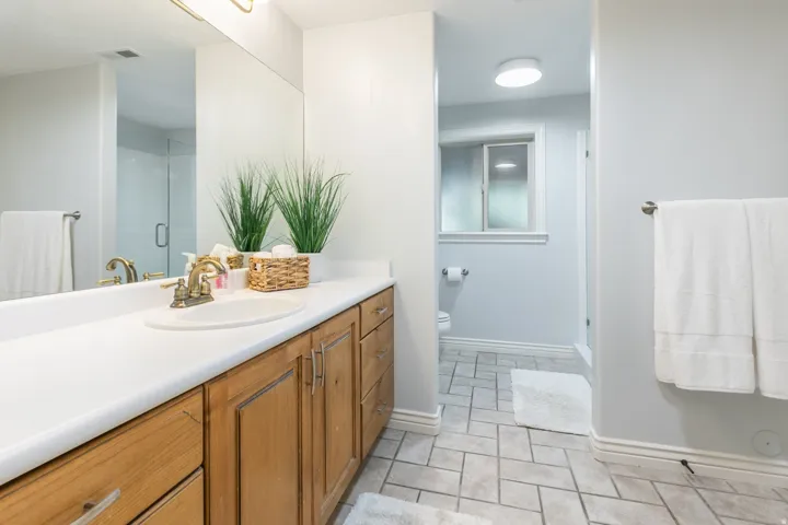 Wood-finish vanity with a white countertop and integrated sink, complemented by a large wall-mounted mirror