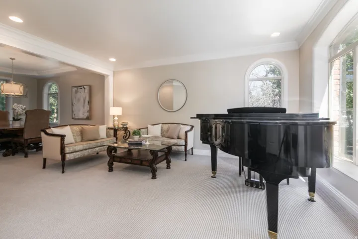 Recessed lighting, arched windows, crown molding, and light-toned carpeting