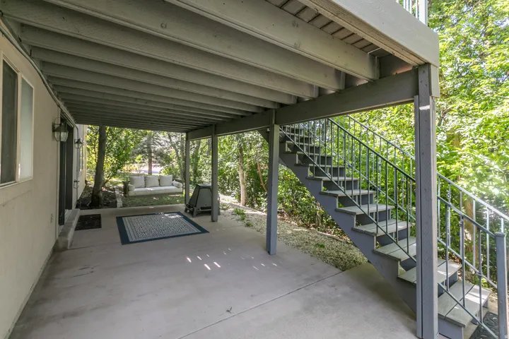 Covered concrete patio with overhead deck structure and exterior lighting