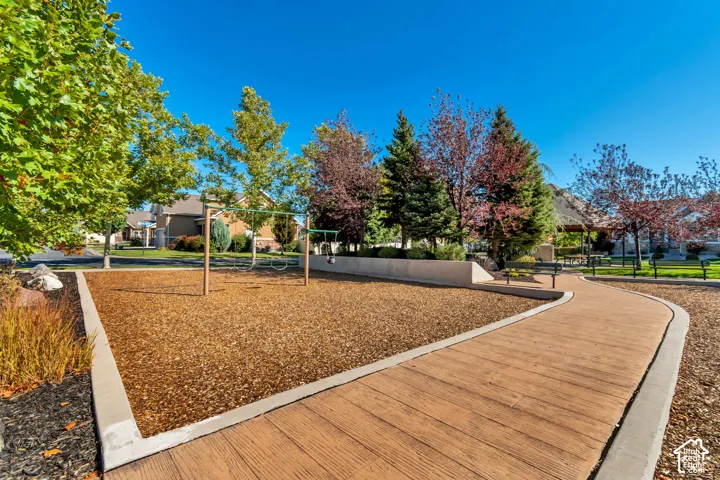 Recreational area featuring a swing set, wood chip ground cover, and a paved pathway