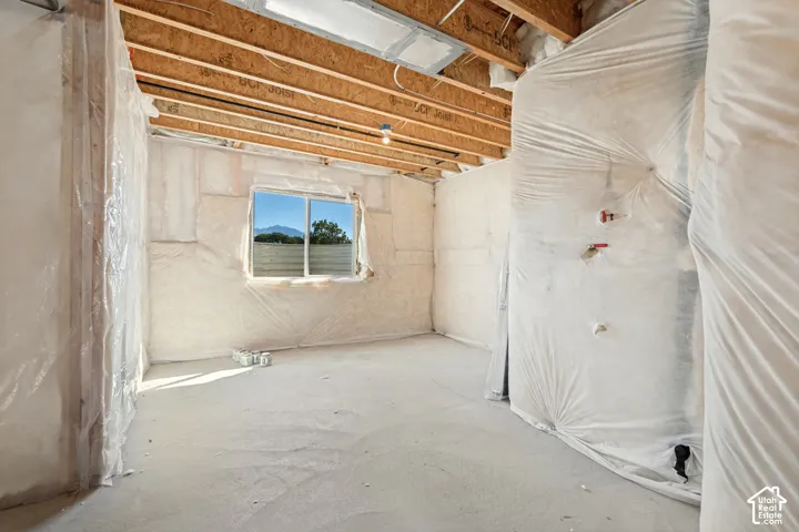 Unfinished space with exposed ceiling joists, insulation-wrapped walls, and a window framing a mountain backdrop