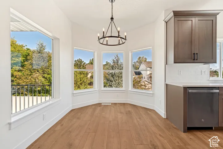 Expansive bay window design, wood-finish flooring, white walls, built-in cabinetry, and a contemporary chandelier