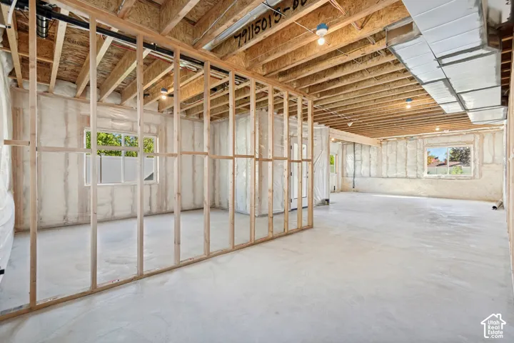 Unfinished basement with exposed ceiling joists, concrete flooring, framed wall partitions, and multiple windows