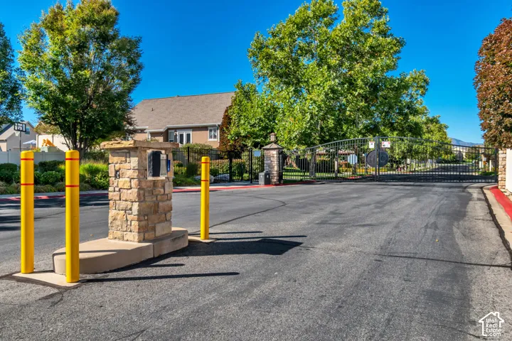 Gated entrance featuring wrought iron gates, stone columns, and paved access