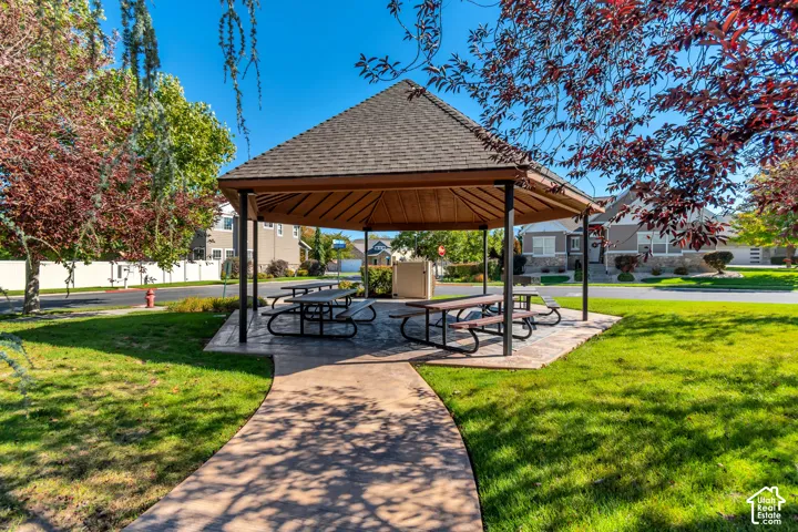 Covered outdoor seating area featuring a shingled roof and concrete flooring