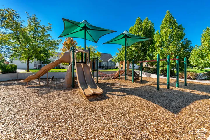 Playground area featuring two slides, climbing elements, and overhead shade structures