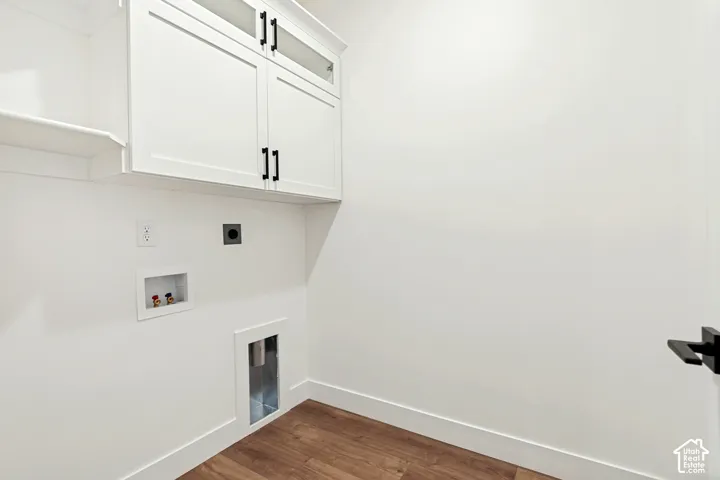 White shaker-style cabinetry with glass inserts, matte black hardware, wood-finish flooring, and a dedicated laundry hookup