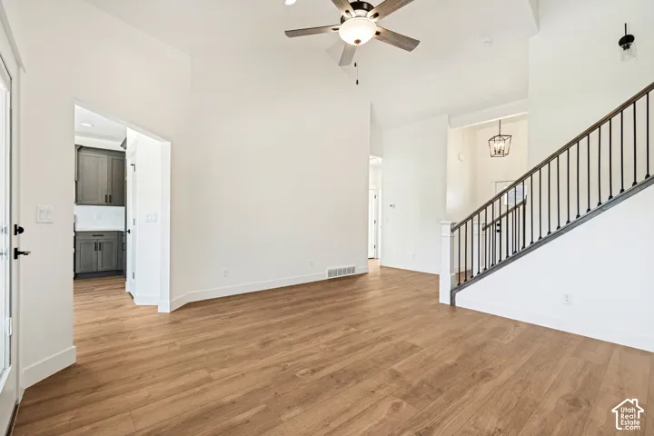 Light wood-finish flooring, vaulted ceilings, and a ceiling fan with integrated lighting